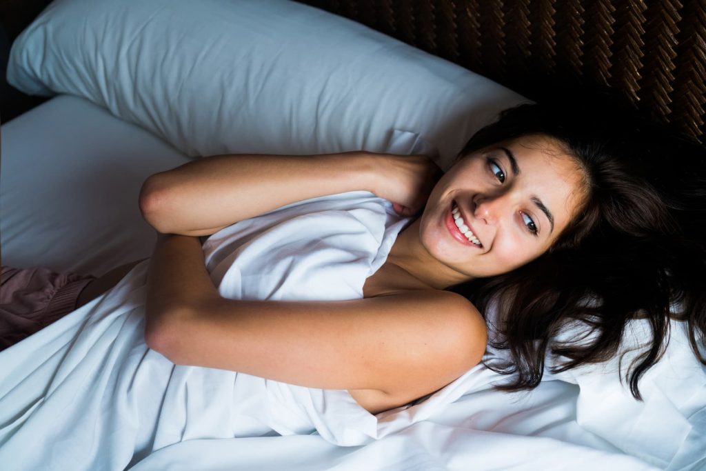 Woman in bed alone happy and smiling.